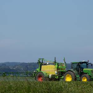 Traktor spritzt Feld mit Insektiziden